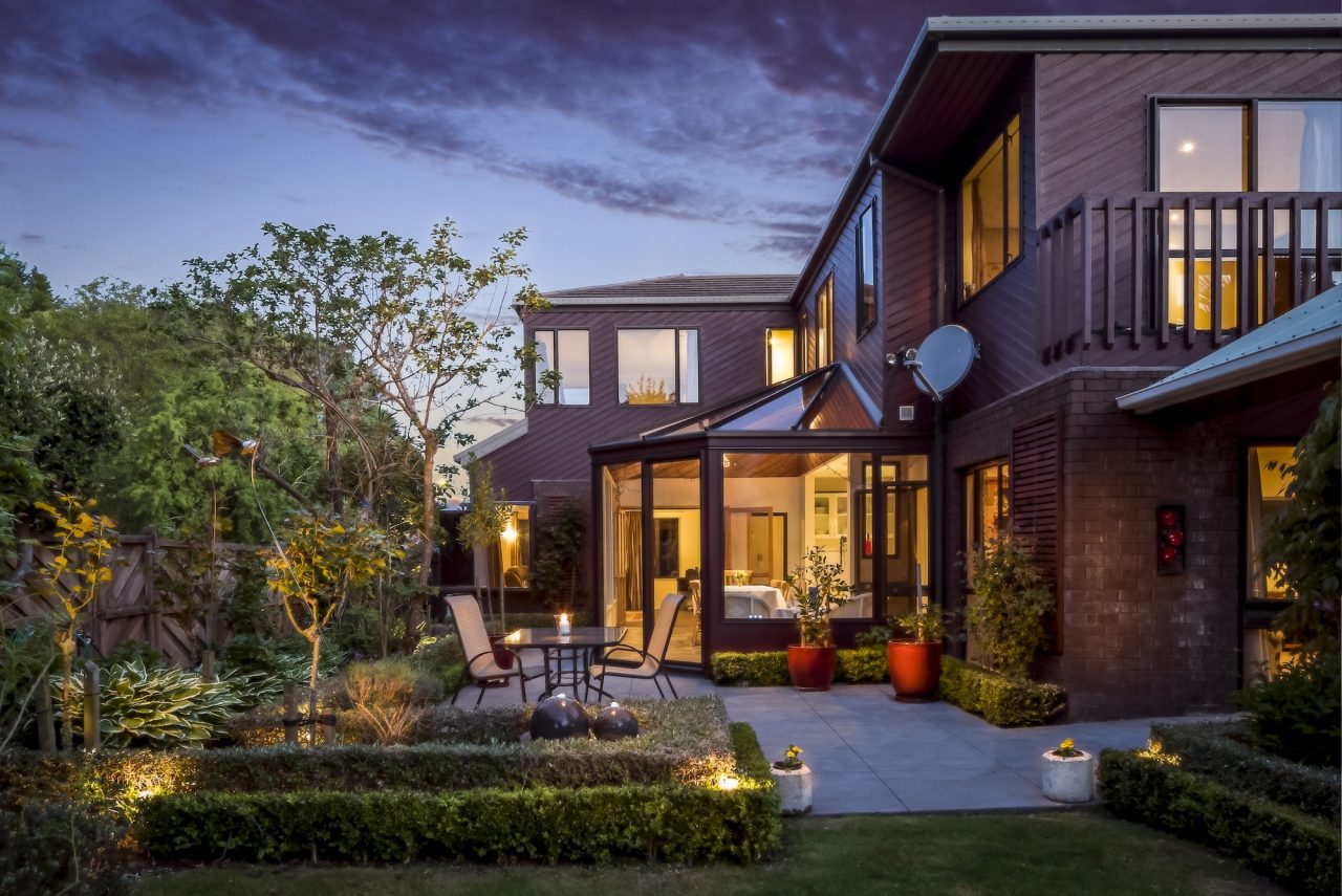 big private house with a garden under the cloudy sky at night